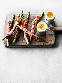 Soft-boiled duck eggs with green asparagus wrapped in bacon
