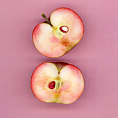 Two apple halves on a pink background