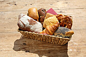 Assorted fresh baked goods in basket on wooden table