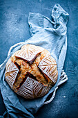 Homemade sourdough bread with cloth on blue background