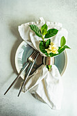 Gardenienzweig mit weißer Blüte auf dem gedeckten Tisch