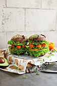 Hausgemachter Fischstäbchen-Burger mit Avocado, Salatblättern und Kräutern