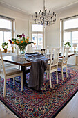 Großer Esstisch mit Holzplatte und weiße Stühle auf Perserteppich in hellem Essbereich