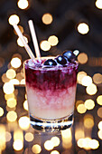 Alcoholic festive fresh blueberry syrup Christmas cocktail in a lowball glass garnished with blueberries