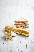 Selection of deli wraps, baguette and sandwhiches filled with chicken and salad, ham and cheese, tomatoes, onion and cheese
