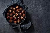 Overhead shot of a pan with roasted chestnuts on dark background