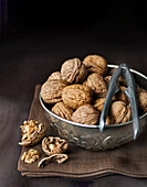 Walnuts with nut cracker in a silver bowl