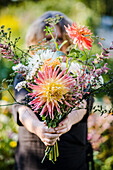 Frau hält Blumenstrauß mit Dahlien