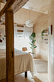 Schlafbereich mit Doppelbett, im Vordergrund rustikale Holzstütze