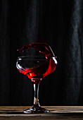 Rotwein mit Schwung im Weinglas vor schwarzem Hintergrund
