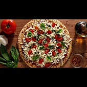 Top pizza with garlic, tomatoes, and basil