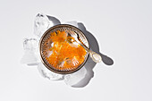 From above orange tobiko caviar served on silver plate with ice with spoon on white background
