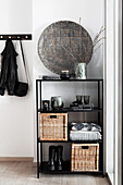 Black shelf with baskets and grey-black decorative objects in the hallway