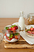 Frische Erdbeeren mit Zucker in einem Glasgefäß auf Holztisch