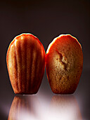 Two madeleines against a dark background