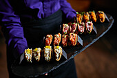 Assorted seafood tacos served as appetizers on a slate platter