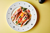 Parma ham and fried egg on mixed vegetables