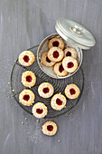 Linzer eyes on a cooling rack and in a biscuit tin