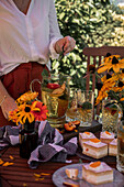 Pfirsich-Eistee und Käse-Sahne-Schnitten auf sommerlich gedecktem Tisch im Freien