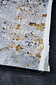 An empty baking tray with crumbs on baking paper