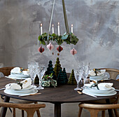 Christmas table setting with white tableware, Advent wreath hanging over it