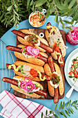 Hot Dogs mit verschiedenen Toppings, eingelegten Zwiebeln, Senf, Ajvar, Sauerkraut