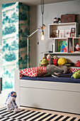 Bed with pillows and stuffed animals, shelves above in the children's bedroom