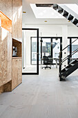 Light room with black metal staircase, office in the background