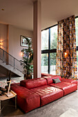 Red leather sofa in high room with floor to ceiling windows