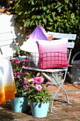 DIY cushion covers in metal basket on garden chair, in front purple coneflower and dahlia