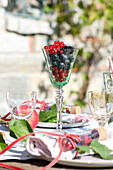 Stem glass filled with berries, as table decoration