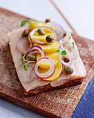 A slice of bread topped with herring, potatoes and capers