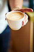 Barista pours milk foam to make latte art