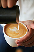 Barista pours milk foam with latte art