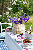 Gedeckter Sommertisch mit Erdbeeren und Salat und mit Rittersporn