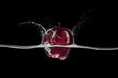 Red apple splashing in water