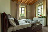 A double bed with an upholstered headboard and a white chest of drawers in a bedroom