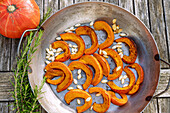 Seared Hokaido pumpkin wedges with roasted pumpkin seeds and a sprig of rosemary