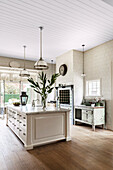 White kitchen island with drawers and marble worktop in country house kitchen