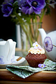 A chocolate muffin with cream and violets