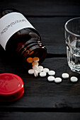 Several aspirin tablets next to a glass of water