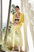 Young brunette woman wearing a striped tankini top, yellow pants and jacket