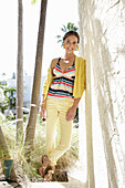 Young brunette woman wearing a striped tankini top, yellow pants and jacket