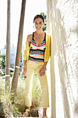 Young brunette woman wearing a striped tankini top, yellow pants and jacket