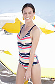 Junge brünette Frau in gestreiftem Badebekleidung am Strand