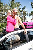 Gut gelauntes Paar in Urlaubsstimmung steht in der Dachfensteröffnung eines Wagens