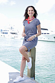 Brunette woman in a striped summer dress by the sea