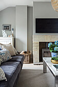 Living room with velvet sofas, marble table, and wood stove, TV above