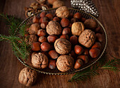 Hazelnuts and walnuts with sprigs of pine needles in a silver bowl