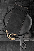 Black pan and kitchen board on a black background